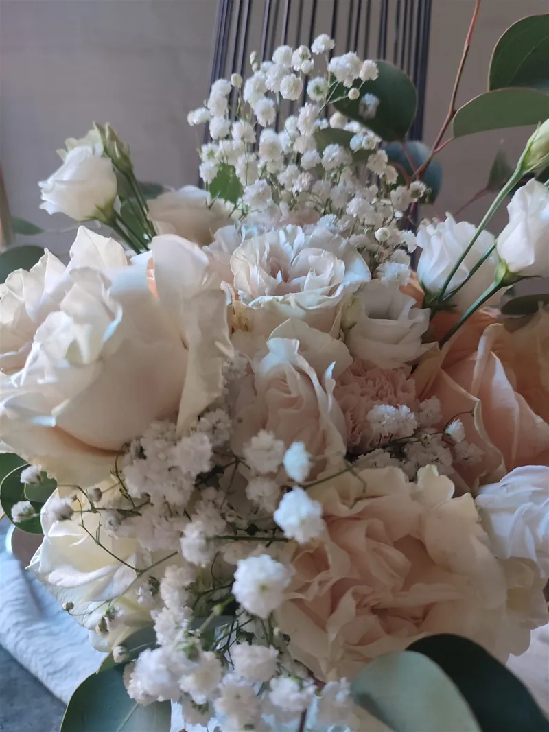 Dicht gebundener Brautstrauß aus cremefarbenen und blassrosa Rosen mit Schleierkraut