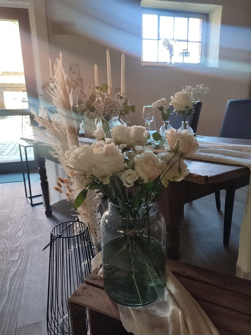 Weiße Rosen in Glasvase mit Pampasgras in der Scheune
