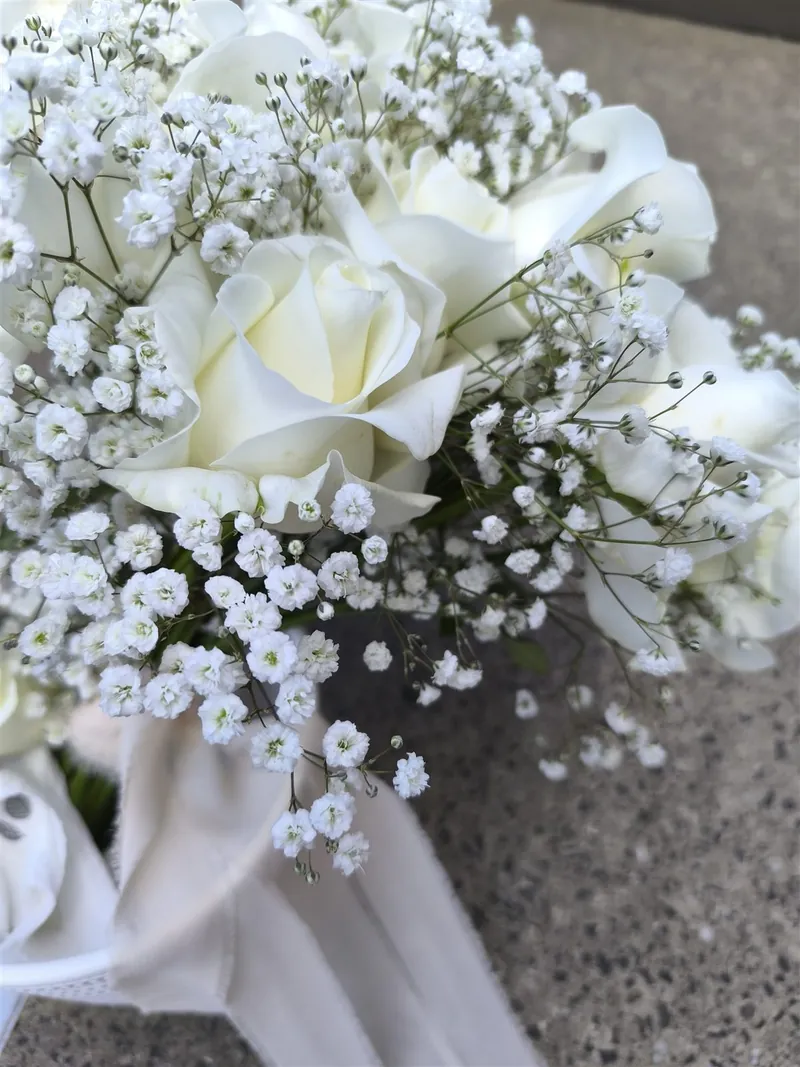 Runder, dichter Brautstrauß aus weißen Rosen mit Schleierkraut