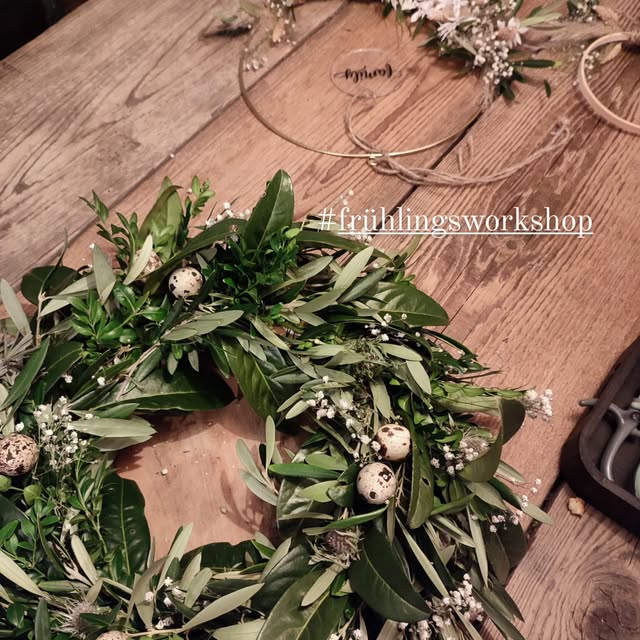 Frühlingskranz aus Olivenzweigen, Buchs und Schleierkraut auf Holztisch