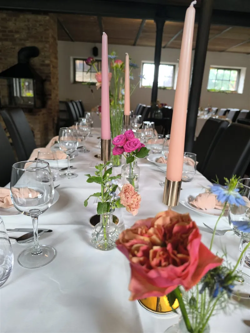 Festlich gedeckte Tafel mit Stabkerzen, Rosen und kleinen Blumenvasen